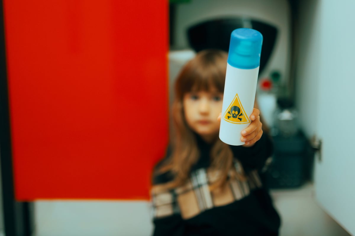 Child in danger handling harmful toxic sprays in the kitchen